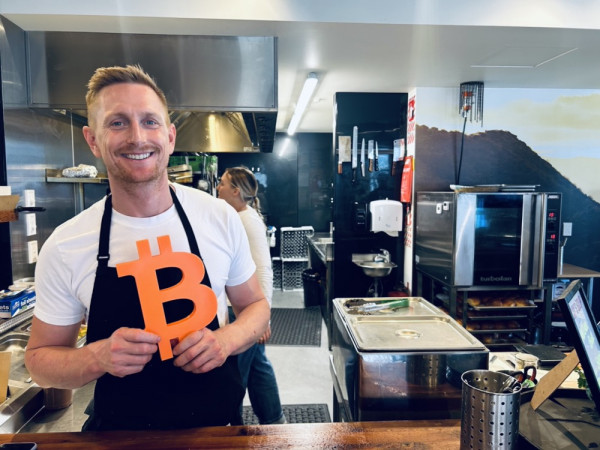 A shopkeeper with the Bitcoin sign in Queenstown